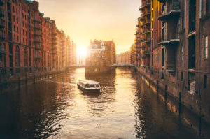 Hamburg warehouse district in golgen hour sunset lit. Water castle palace and tourist visting boat trip in river. Old warehouse port, Germany, Europe. Hamburg warehouse district in golgen hour sunset lit. Water castle palace and tourist visting boat trip in river. Old warehouse port, Germany, Europe.